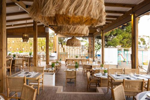 a restaurant with tables and chairs and a large window at Skiathos Thalassa Cape, Philian Hotels and Resorts in Megali Ammos