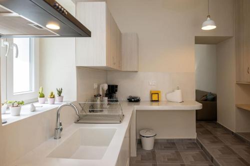 a large white kitchen with a sink and a window at MALAMATENIA'S HOUSE in Tinos Town