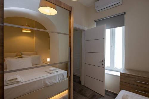 sypialnia z lustrem, łóżkiem i oknem w obiekcie MALAMATENIA'S HOUSE w mieście Tinos
