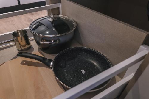 a frying pan in a drawer in a kitchen at Two Steps Apartments Tirana in Tirana