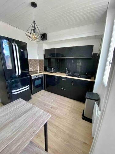 une cuisine avec des armoires noires et un plancher en bois dans l'établissement Appartement proche des remparts - Avignon, à Avignon