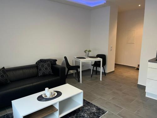 ein Wohnzimmer mit einem schwarzen Sofa und einem Tisch in der Unterkunft Monteur Wohnung in Hagen