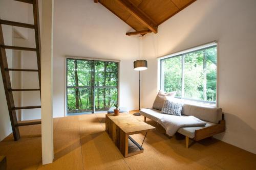 a living room with a couch and a table and windows at LOOF Tiny House Camp in Fuefuki