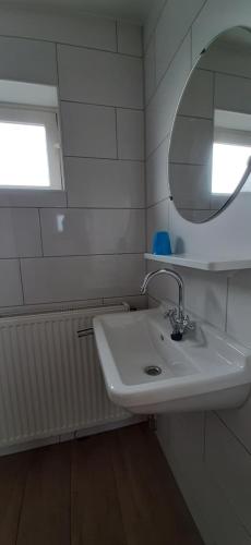 a white bathroom with a sink and a mirror at Logies Plevierstraat in De Koog