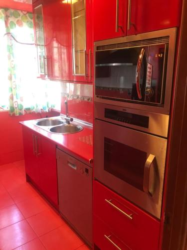 cocina roja con fregadero y microondas en MilanG, en Madrid