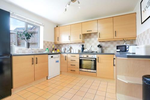 a kitchen with wooden cabinets and a black refrigerator at Grange House with Free Parking, Garden, Superfast Wifi and Smart TVs with Netflix by Yoko Property in Northampton