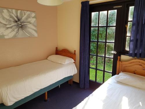 a bedroom with two beds and a window at Tolroy Manor Holiday Park in Hayle