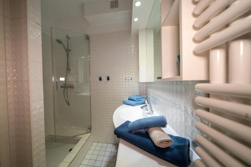 a bathroom with a sink and a shower with blue towels at Hus an de Marsch in Midlum