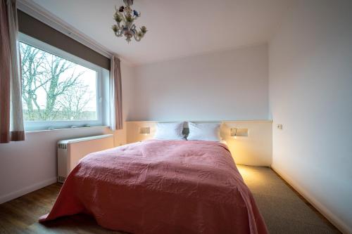 a bedroom with a bed with a large window at Hus an de Marsch in Midlum