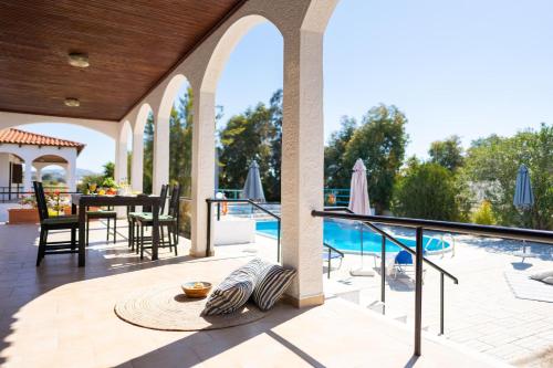 an outdoor patio with a table and chairs and a pool at Villas Mina in Gennadi
