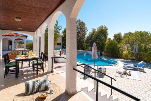 an outdoor patio with a table and a swimming pool at Villas Mina in Gennadi