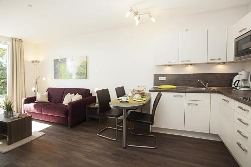 eine Küche und ein Wohnzimmer mit einem Tisch und einem Sofa in der Unterkunft Residenz am Balmer See - BS 03 mit Wellnessbereich in Balm
