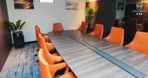 a conference room with a wooden table and orange chairs at OTIA HOTEL in Maputo