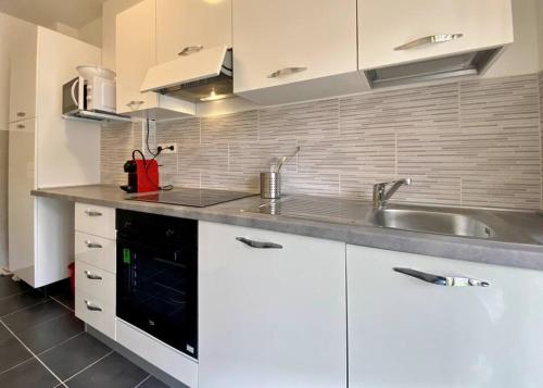 une cuisine avec des armoires blanches et un évier dans l'établissement L Alicante Carré d'Or 2 pieces Terrasse Climatise, à Menton