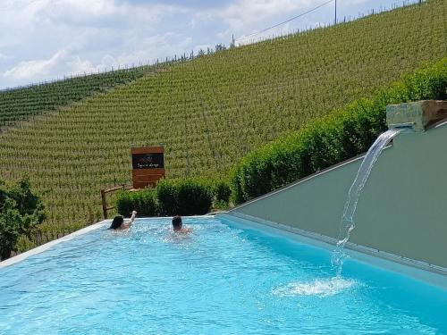 two people in a swimming pool with a water fountain at Sogno in Langa in Monforte dʼAlba