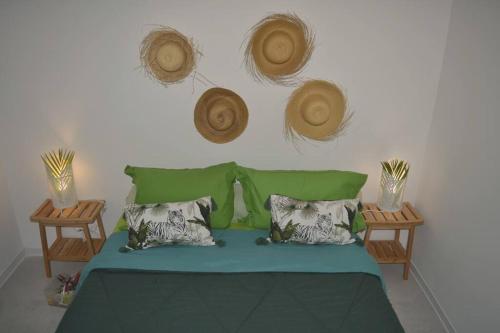 1 dormitorio con 1 cama con 2 mesas y sombreros en la pared en VILLA BAMBOU Domaine à l'ombre du Bambou jusqu'à 6 pers, Parc national de la Guadeloupe, en Le Gosier