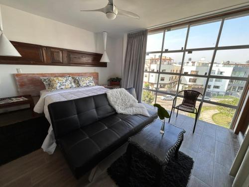 1 dormitorio con cama, sofá y ventana grande en Amplio, cómodo y moderno apartamento cerca al Mall en Lima