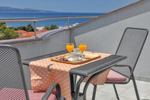 einen Tisch mit zwei Gläsern Orangensaft auf dem Balkon in der Unterkunft Villa Juric in Baška Voda