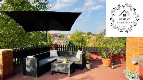 eine schwarze Couch und ein Regenschirm auf einer Terrasse in der Unterkunft Kisház Apartman in Eger