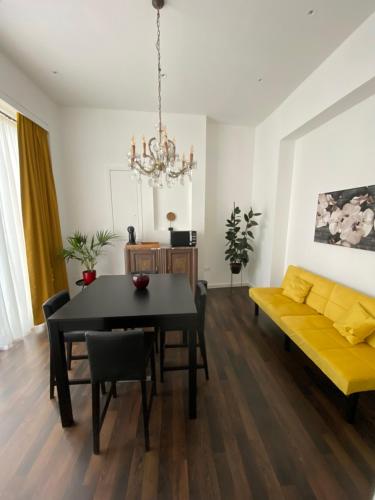 a living room with a table and a yellow couch at “De Koelemert” in Aalst