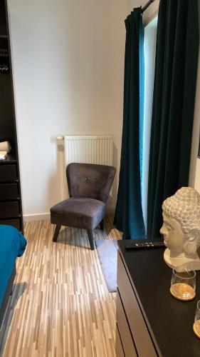 a room with a chair and a bust on a dresser at “De Koelemert” in Aalst