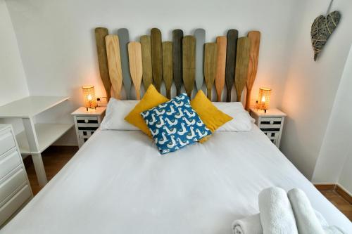 1 dormitorio con cama blanca y cabecero de madera en Apartamentos La Perla Azul, en Málaga