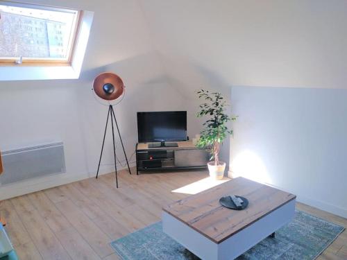 uma sala de estar com uma televisão de ecrã plano e uma mesa em SOUS LES TOITS em Troyes