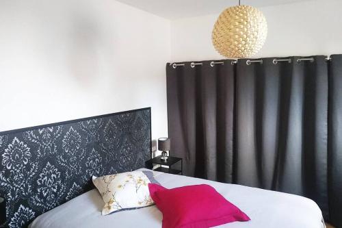 uma cama com uma cabeceira preta e uma almofada vermelha em SOUS LES TOITS em Troyes