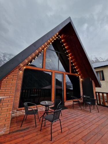 a deck with chairs and a table on a building at Kazbegi Hut Cottage in Stepantsminda