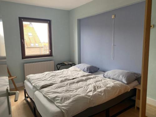 een bed in een kamer met een raam bij Zeezicht Blankenberge in Blankenberge