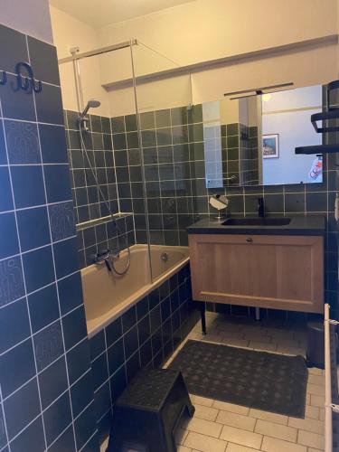 een badkamer met een wastafel, een bad en een spiegel bij Zeezicht Blankenberge in Blankenberge