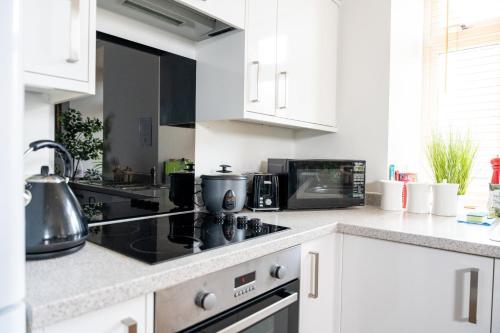 a kitchen with white cabinets and a stove top oven at Modern & Spacious flat in the Centre of Bristol! in Bristol
