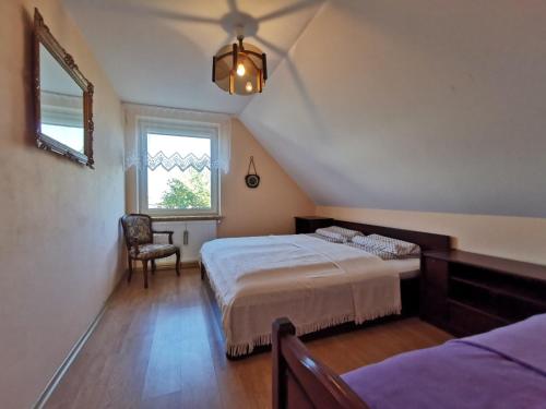 - une chambre mansardée avec un lit et une fenêtre dans l'établissement Duży dom w malowniczym miejscu na Kociewiu, 