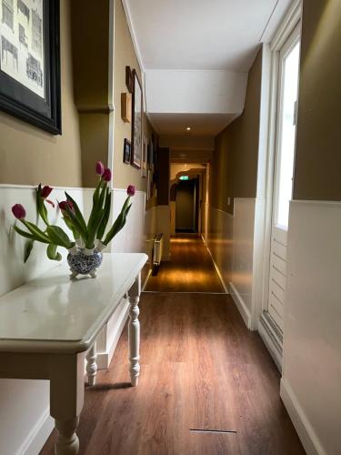 a hallway with a table with a vase of flowers on it at Hotel Old Quarter in Amsterdam