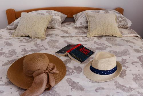 ein Bett mit zwei Hüten und ein Buch darauf in der Unterkunft LightHouse Apartments in Tivat