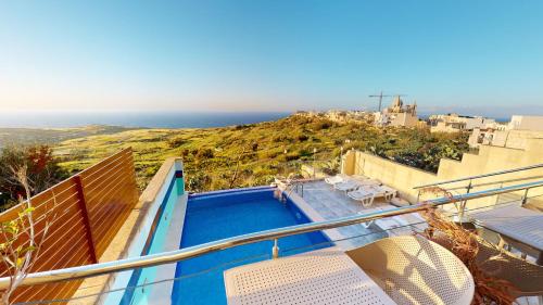uma piscina com cadeiras e vista para o oceano em Dubhlina - Luxury Bed & Breakfast - Gozo em Żebbuġ