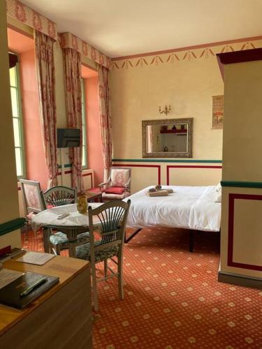 une chambre avec un lit, une table et des chaises dans l'établissement La Mascotte des thermes de Montbrun les bains, à Montbrun-les-Bains
