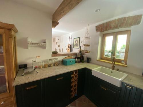a kitchen with black cabinets and a sink and a window at Das Hexenhaus: Haus im Wald in Rinchnach