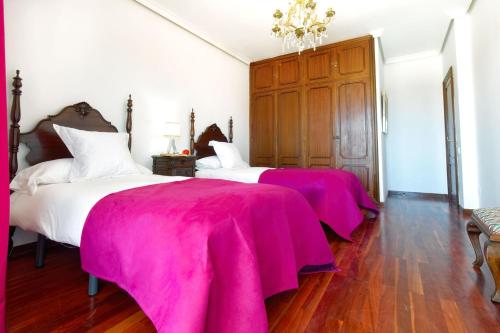 Dos camas en una habitación con mantas rosas. en La Ideal Mansion by VillaGranCanaria, en Tafira