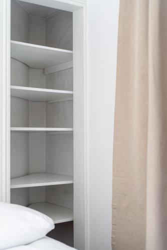 a bedroom closet with white shelves and a bed at "Tuulensuu" - Historical 2BR Apartment with Sauna & Great Location, Hosted by 2ndhomes in Tampere