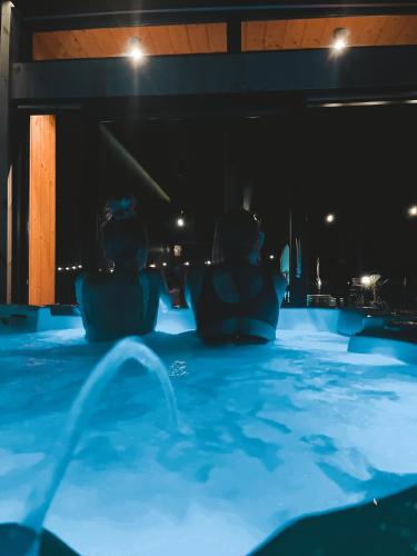 dos personas sentadas en una piscina por la noche en 2 STODOŁY Chillout, en Dziwnów