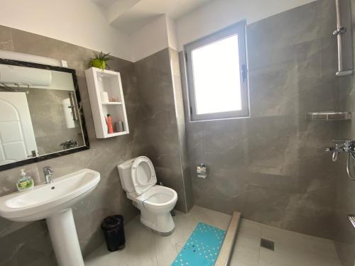 a bathroom with a white toilet and a sink at Your Apartment in Pogradec
