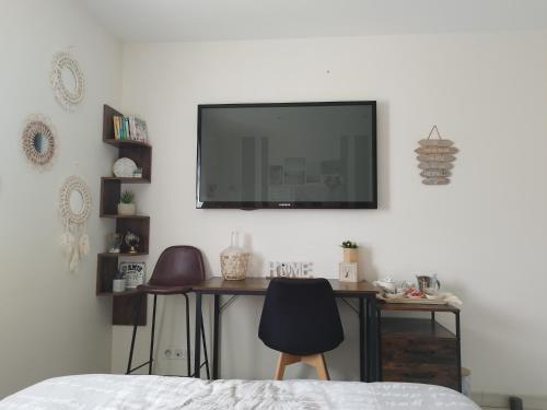 Schlafzimmer mit einem Schreibtisch und einem TV an der Wand in der Unterkunft Chambre d'hôtes salle d'eau et WC privés, véranda,extérieurs et piscine chauffée in Guérande