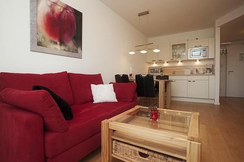ein Wohnzimmer mit einem roten Sofa und einem Couchtisch in der Unterkunft Residenz am Balmer See - BS 01 mit Wellnessbereich in Balm