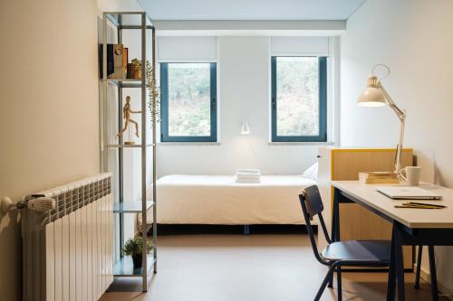 Una habitación con escritorio y cama y una habitación con en micampus Covilhã en Covilhã