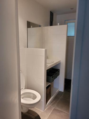 La salle de bains blanche est pourvue de toilettes et d'un lavabo. dans l'établissement Mini villa au bord de la mer, proche Moriani (Corse), à Poggio-Mezzana