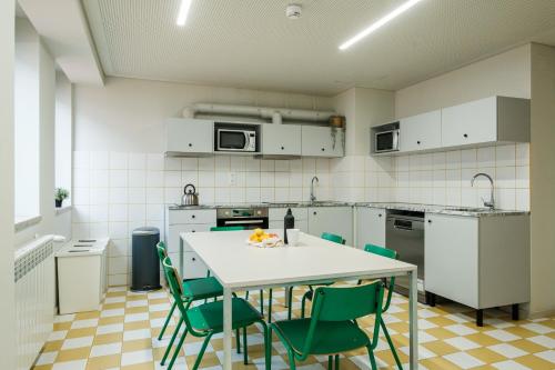 cocina con mesa blanca y sillas verdes en micampus Covilhã en Covilhã
