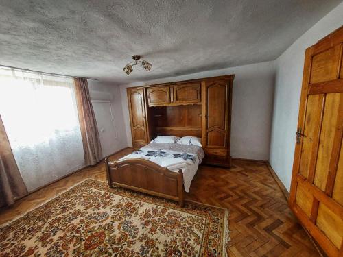 a bedroom with a bed with a wooden headboard and a rug at Casă de vacanță Danube in Moldova Nouă