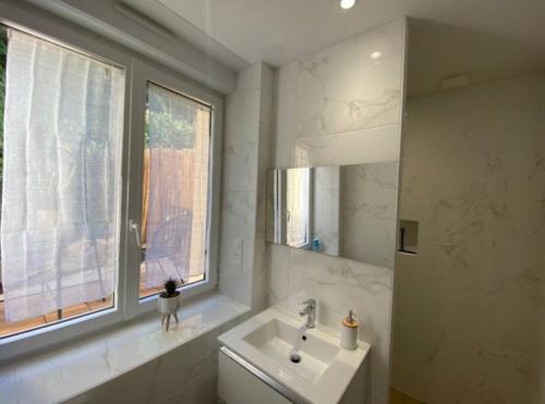 a white bathroom with a sink and a window at Appartement avec terrasse in Quimper