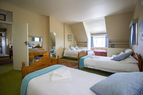 ハンスバーイにあるHolte vir die Voet Akkommodasieのベッド3台とバスルームが備わるホテルルームです。